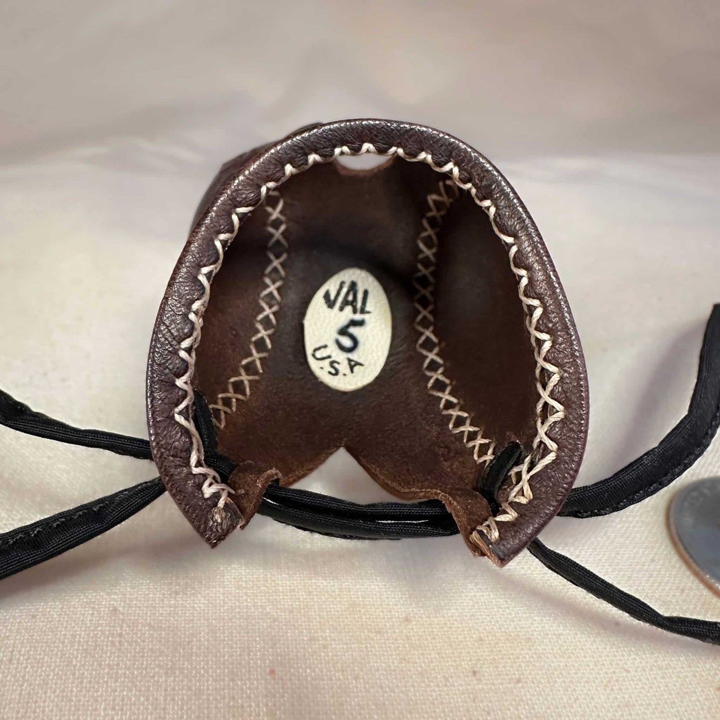 Mini falcon hood made of brown kangaroo leather with a top ornament looking at the inside.