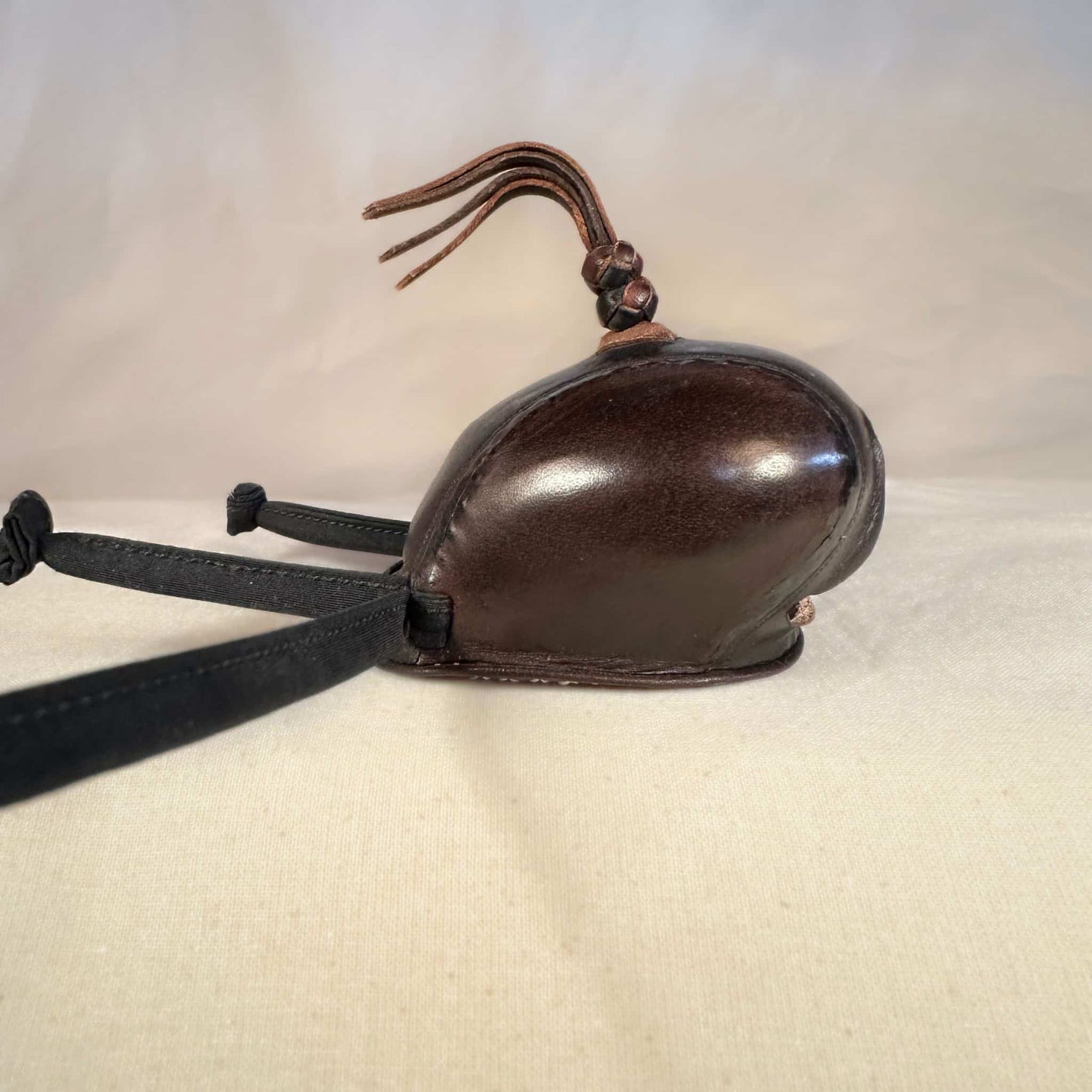 Falcon hood made of two-tone brown calf leather with a double knot top ornament in a right-side view.