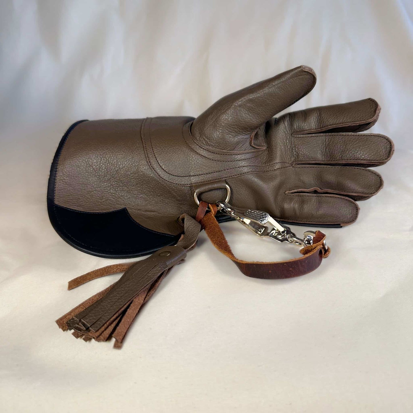 A long short-cuff brown falconry gauntlet made with kangaroo leather looking at the palm with the (not included but available for purchase) French snap and leather thong.