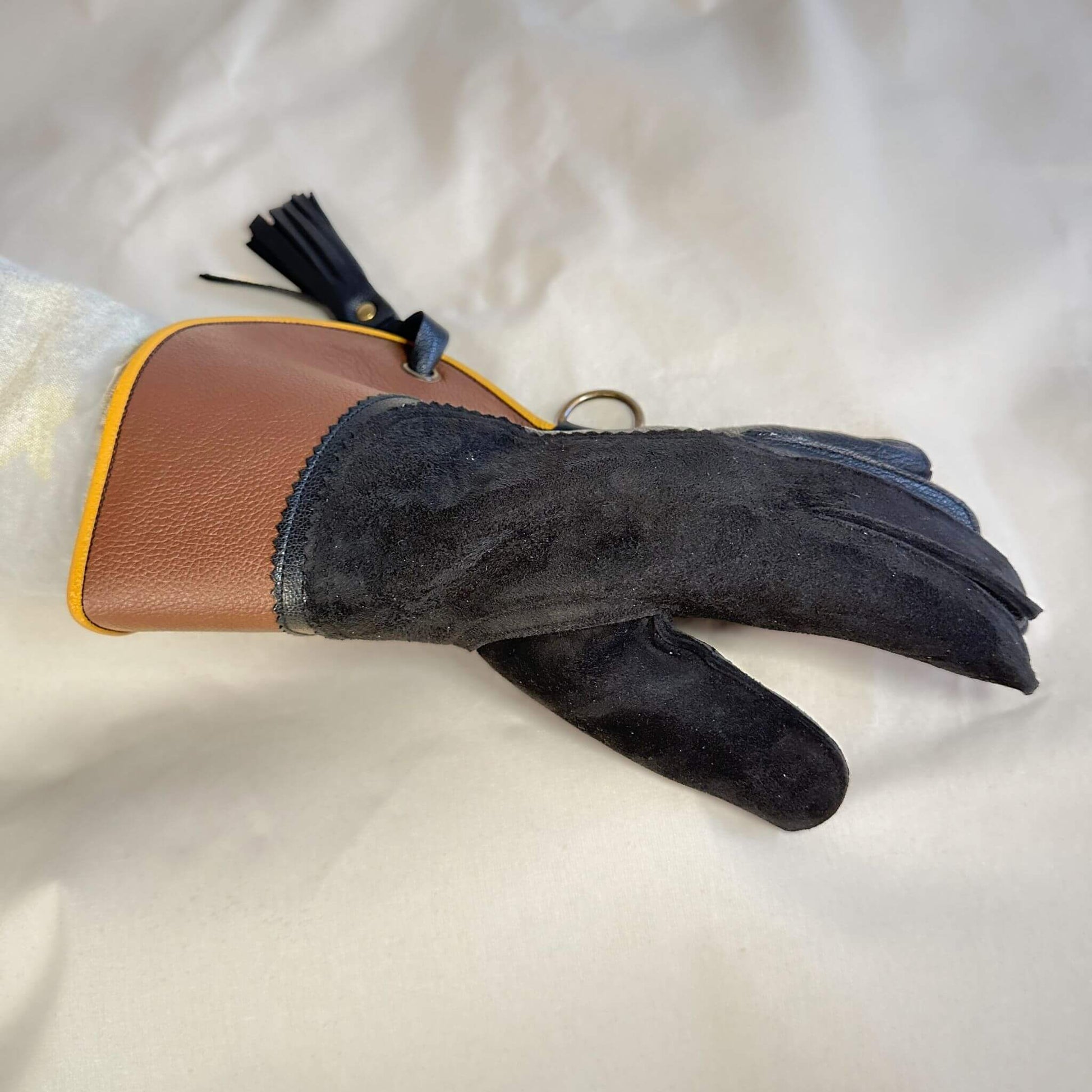 A short half-cuff falcon gauntlet made with brown and black suede deer leather looking at the back of the hand.