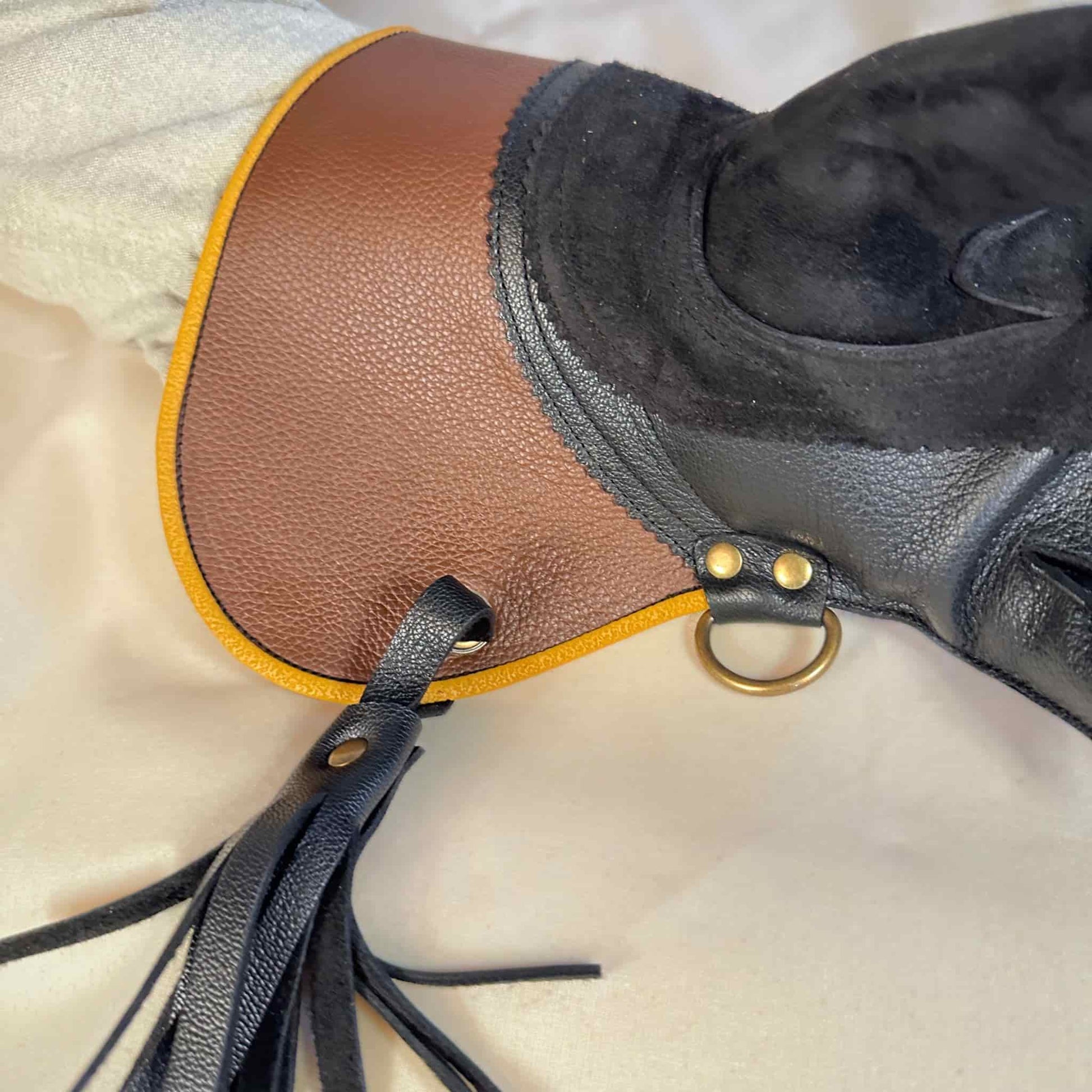 A short half-cuff falcon gauntlet made with brown and black suede deer leather looking at a detail of the cuff and tassel.