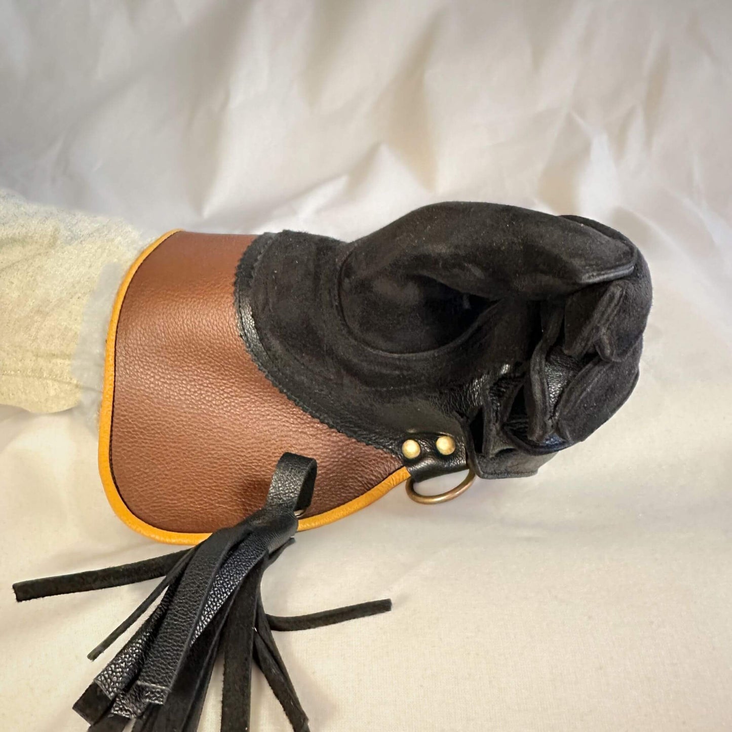 A short half-cuff falcon gauntlet made with brown and black suede deer leather looking at the closed fist.