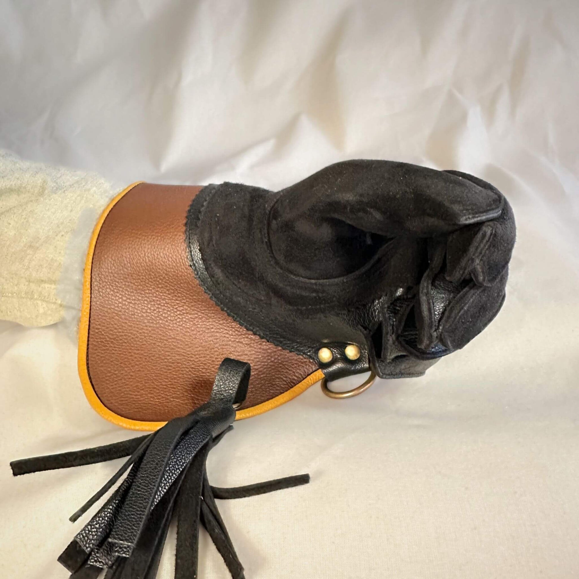 A short half-cuff falcon gauntlet made with brown and black suede deer leather looking at the closed fist.
