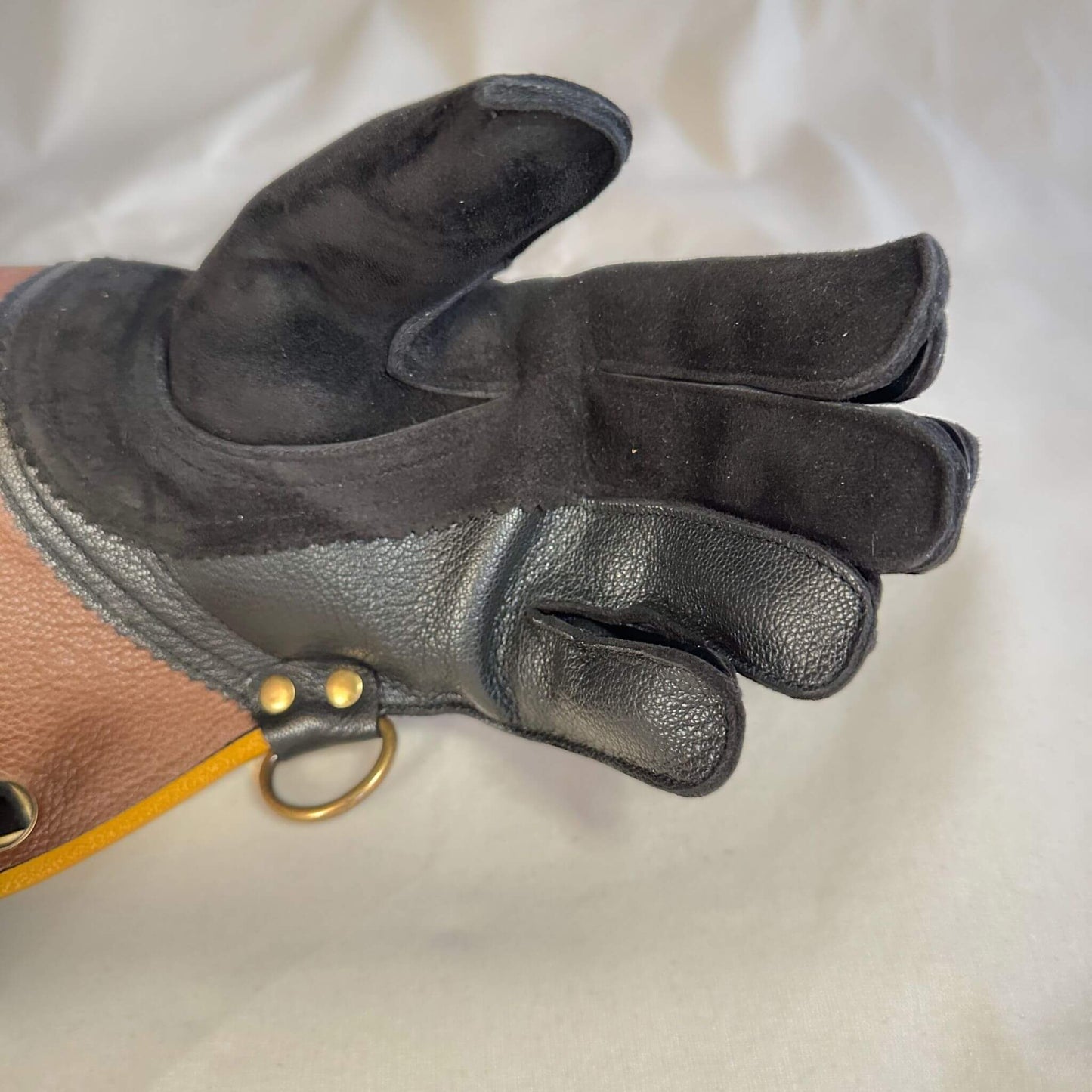 A short half-cuff falcon gauntlet made with brown and black suede deer leather looking at a detail of the palm and seams.