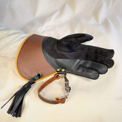 A short half-cuff falcon gauntlet made with brown and black suede deer leather looking at the palm with the (not included but available for purchase) French snap and leather thong.