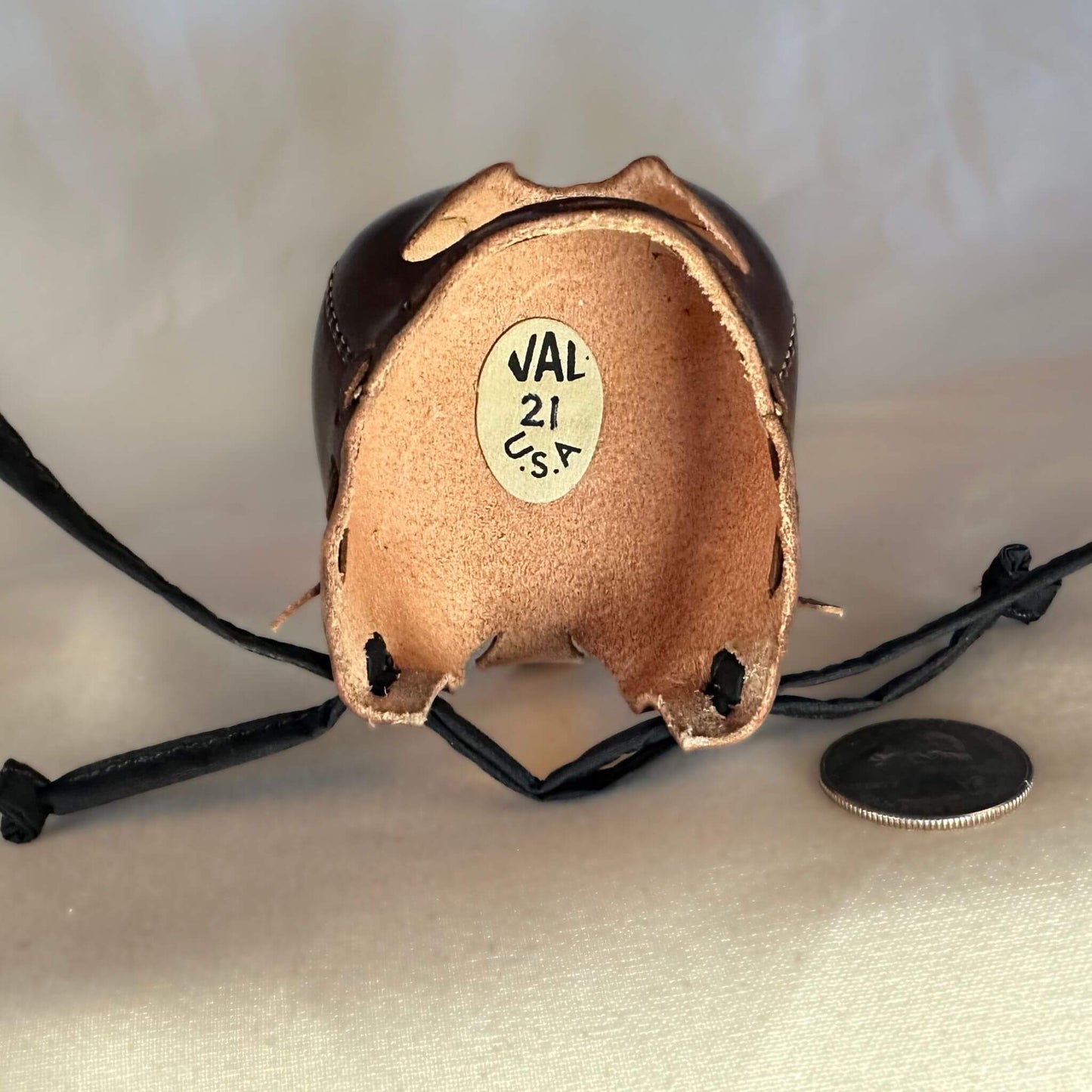 Falcon hood made of brown calf leather with a double knot top ornament looking inside.