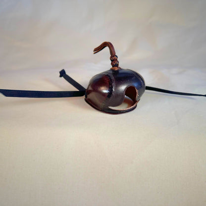Falcon hood made of two-tone brown calf leather with a double knot top ornament at a three-quarter view.