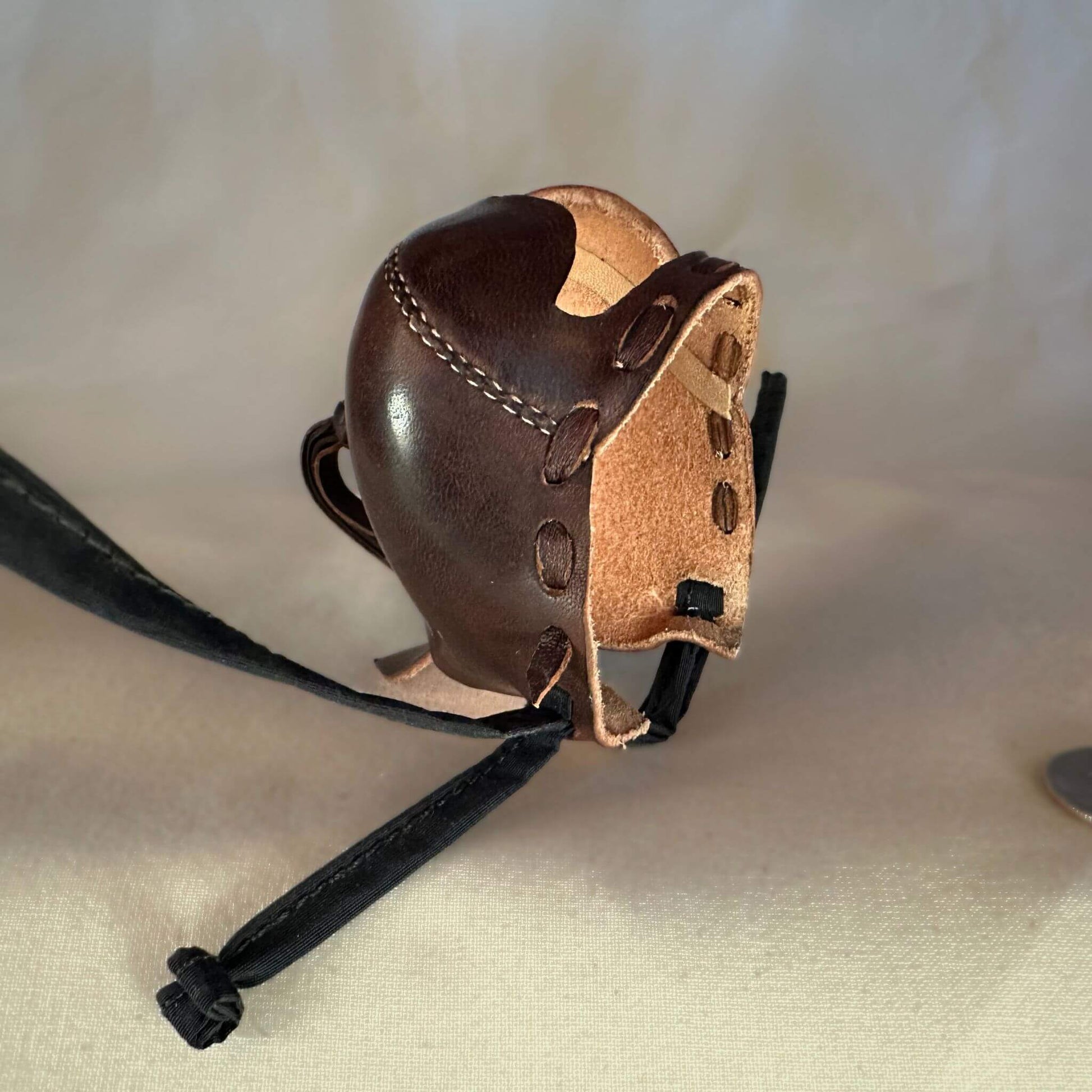 Falcon hood made of brown calf leather with a double knot top ornament pointing upwards.