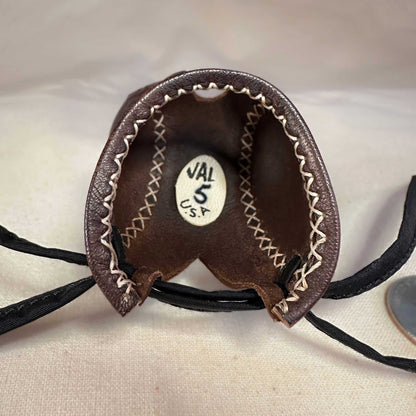 Mini falcon hood made of brown kangaroo leather with a top ornament looking at the inside.