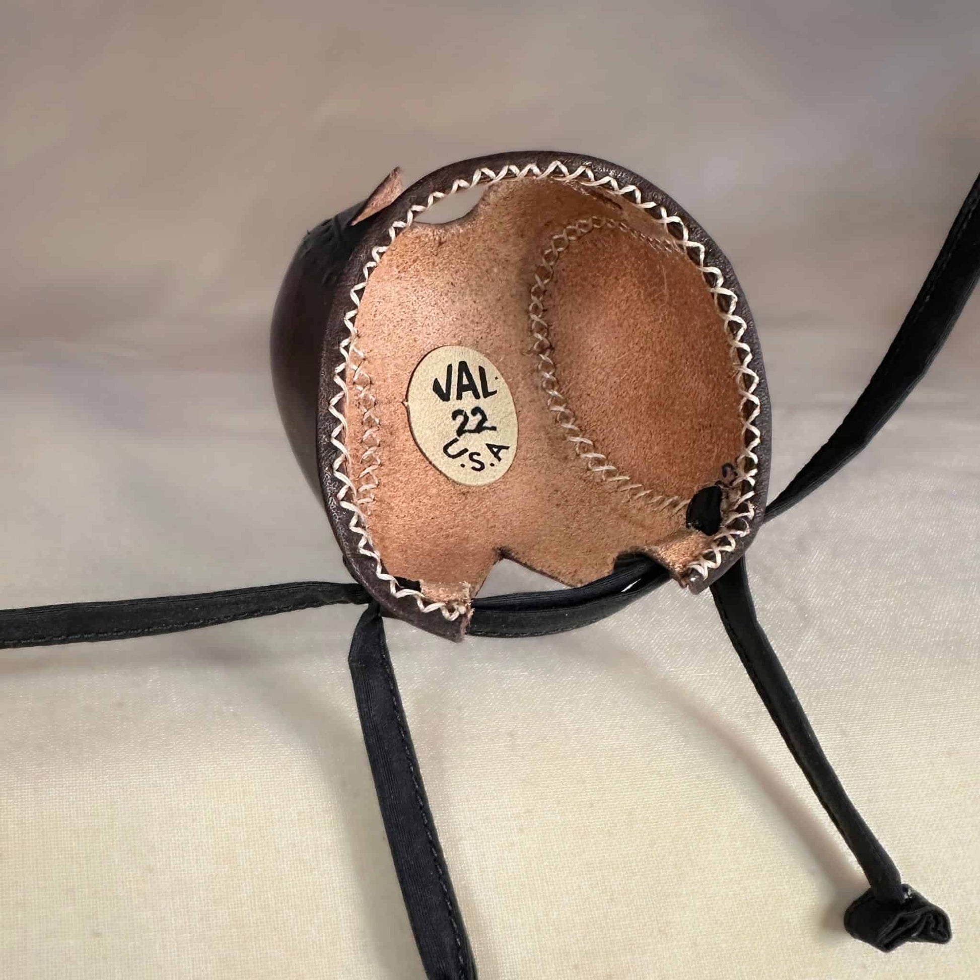 Falcon hood made of two-tone brown calf leather with a double knot top ornament looking at the inside.