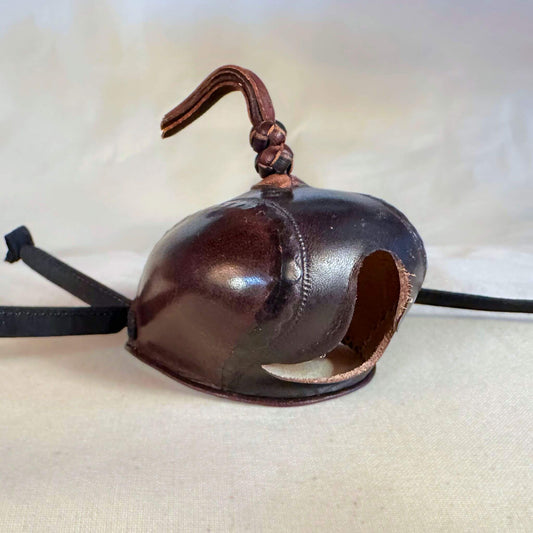 Falcon hood made of two-tone brown calf leather with a double knot top ornament at a three-quarter view.