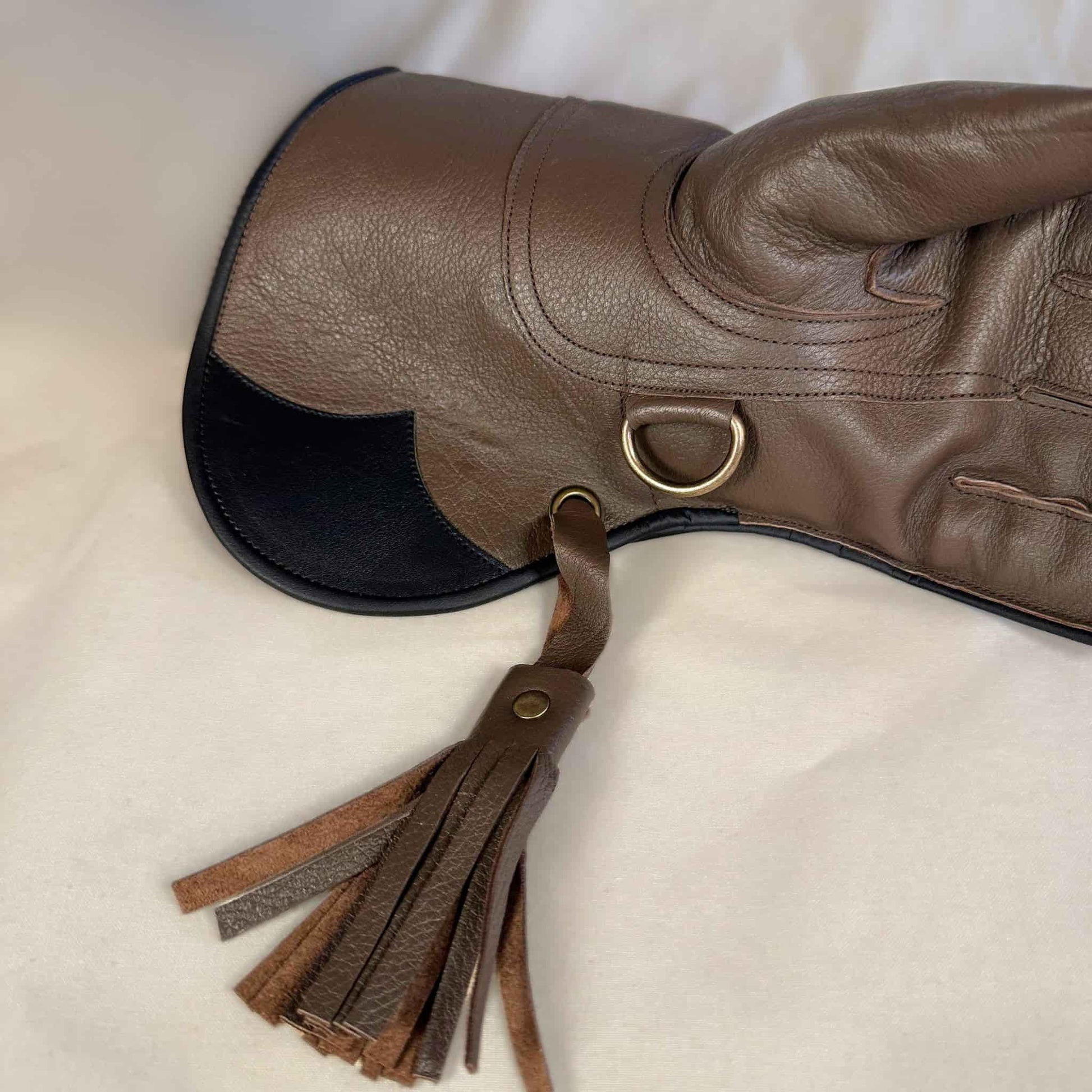 A long short-cuff brown hawk and falcon gauntlet made with water resistant kangaroo leather looking at a detailed view of the cuff and tassel.